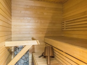 Een sauna met houten banken en een stenen vloer.