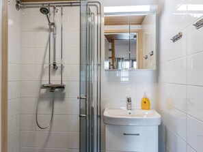 Une salle de bain moderne avec une douche à parois de verre, un lavabo blanc et un miroir au-dessus.