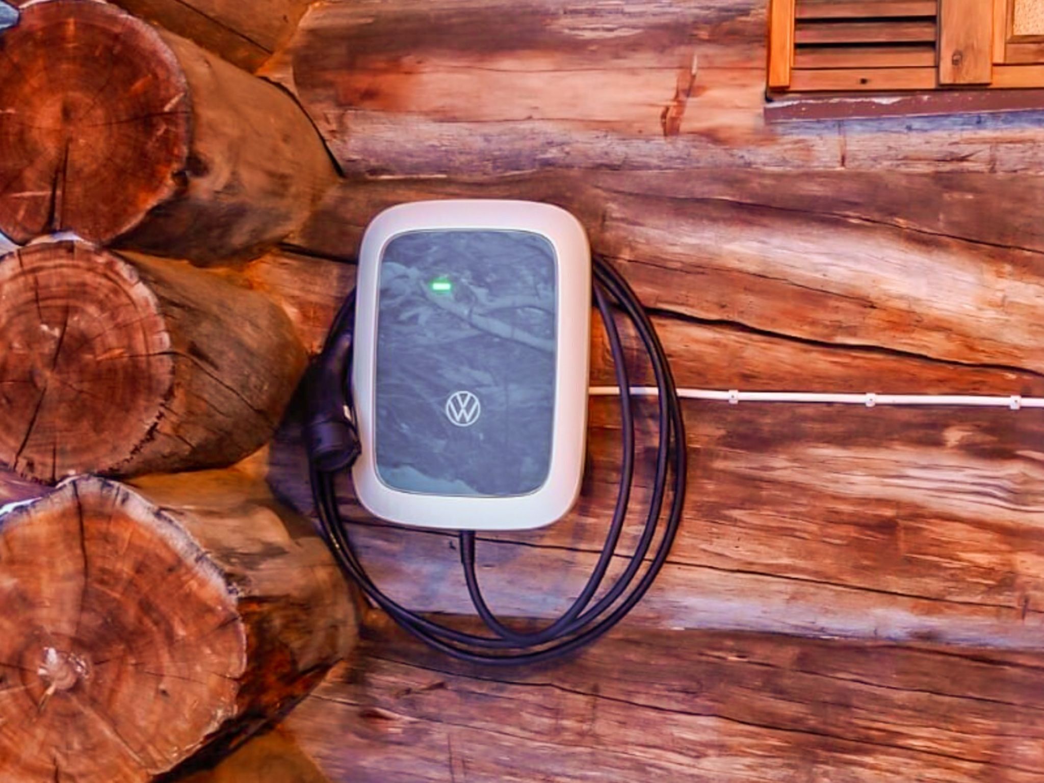 A portable power bank on a wooden surface with visible tree stumps.