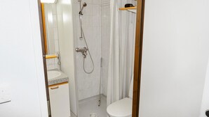 Une salle de bain avec douche, toilettes et lavabo.