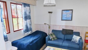 Une pièce comprenant un lit, un canapé, une petite table et une lampe.