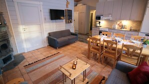 Ein gemütliches Wohnzimmer mit Kamin, einem an der Wand befestigten Fernseher und einem Essbereich mit Holzmöbeln.