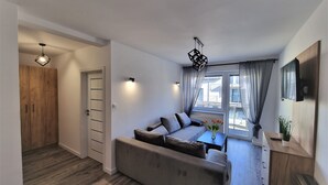 A modern living room with a sofa, a dining table, and a TV mounted on the wall. - Willa Sky (Wladyslawowo)