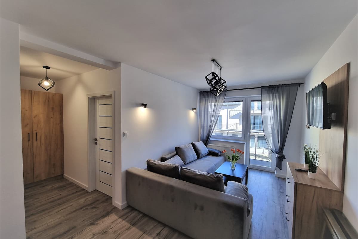 Un salon moderne avec un canapé, une table à manger et un téléviseur fixé au mur.