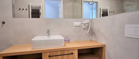 A modern bathroom with a wooden vanity, a white sink, a mirror, and a toilet.