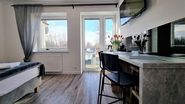 A modern room with a bed, a desk, a chair, a TV, and large windows. - Willa Sky (Wladyslawowo)