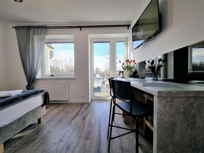 A modern room with a bed, a desk, a chair, a TV, and large windows. - Willa Sky (Wladyslawowo)