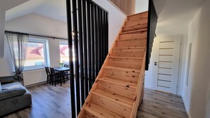 A modern interior with a wooden staircase, a dining area, and a sofa. - Willa Sky (Wladyslawowo)