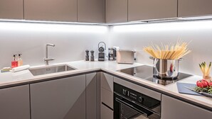 Una cocina moderna con lavavajillas integrado, un lavamanos de acero inoxidable y una campana extractora.