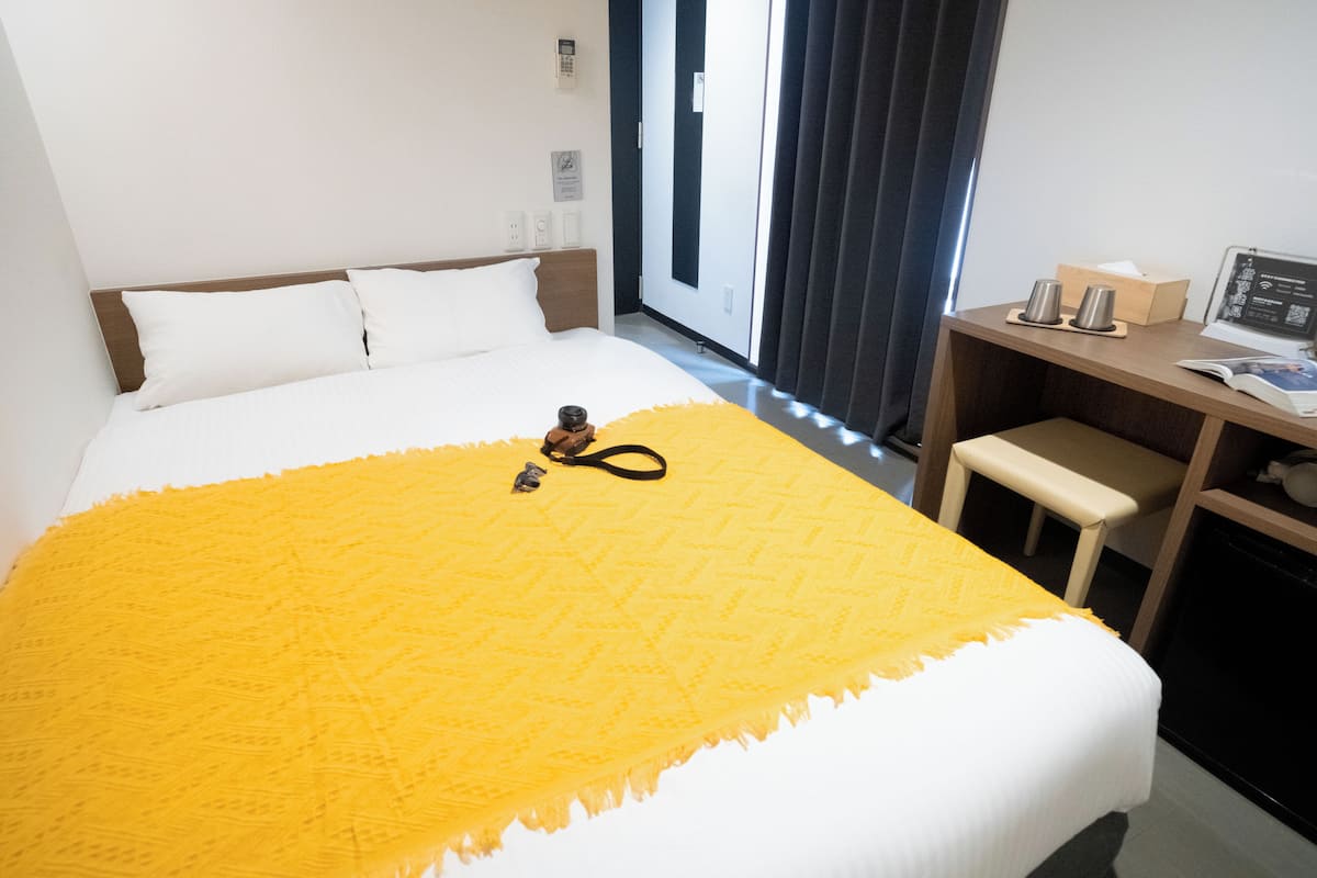 A hotel room with a bed, a desk, and a chair.