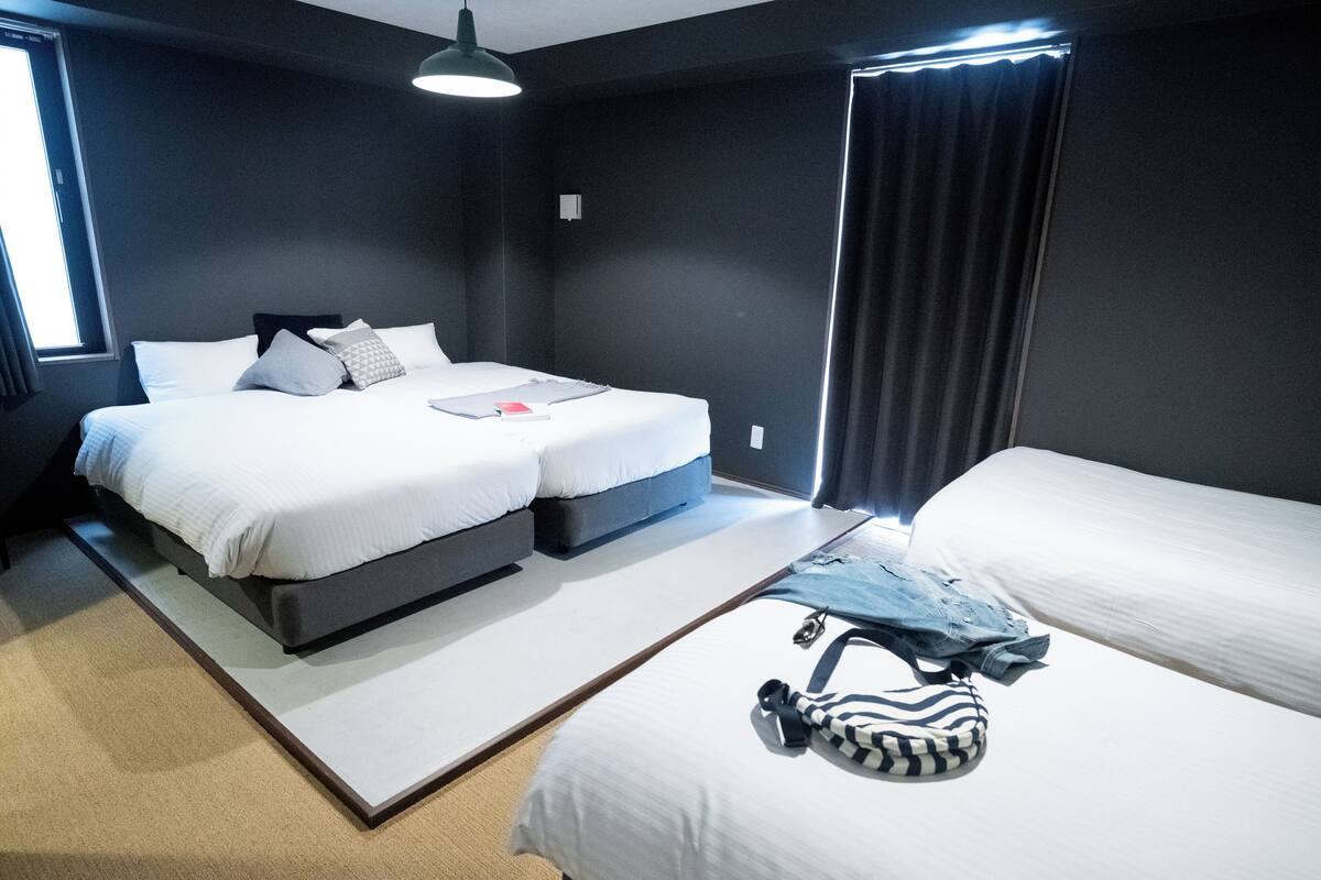 A modern hotel room with a large bed, a smaller bed, and a desk.