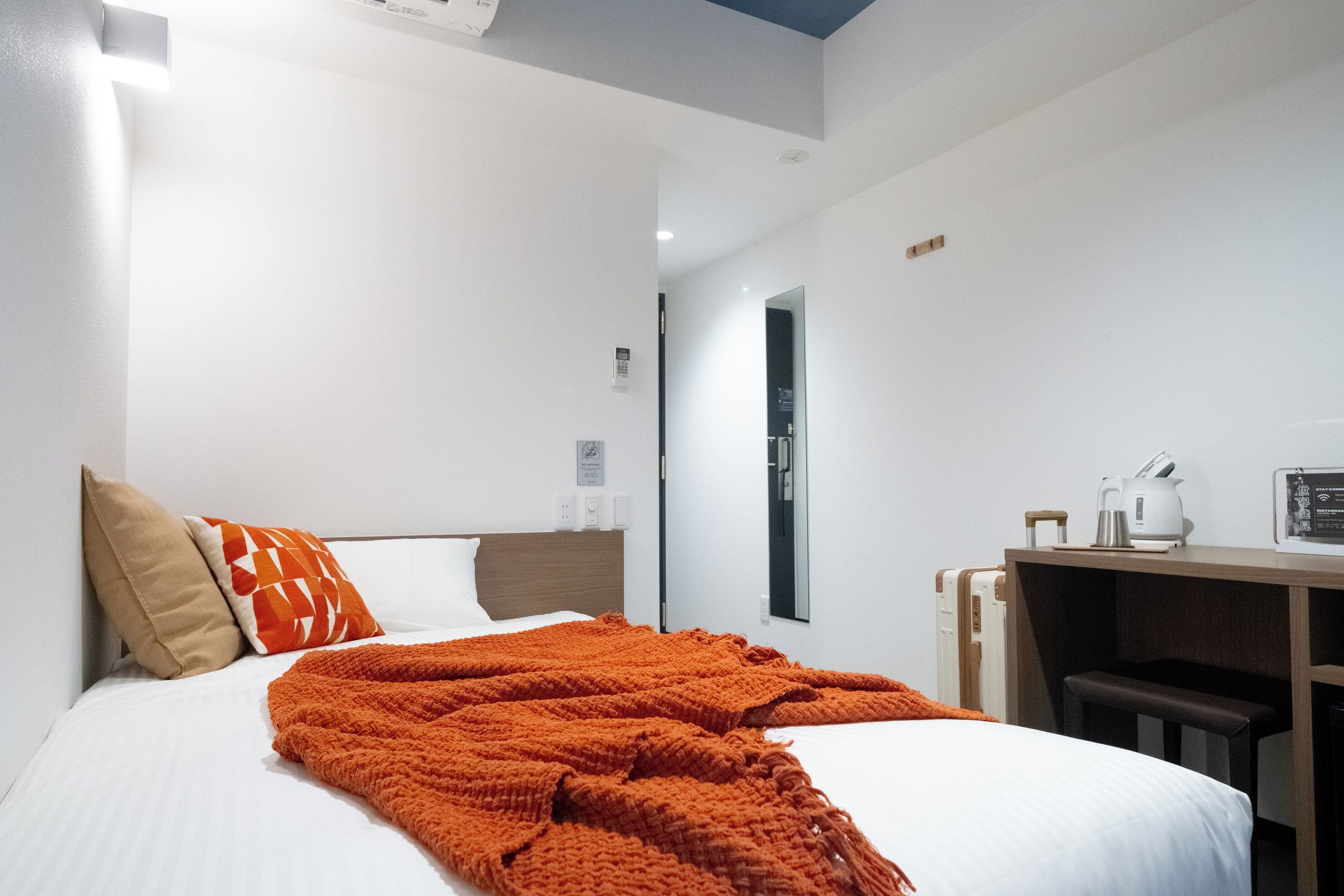A hotel room with a bed, a desk, and a chair.