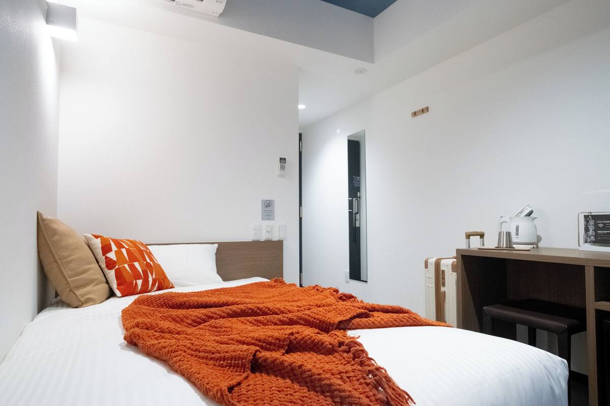 A hotel room with a bed, a desk, and a chair.