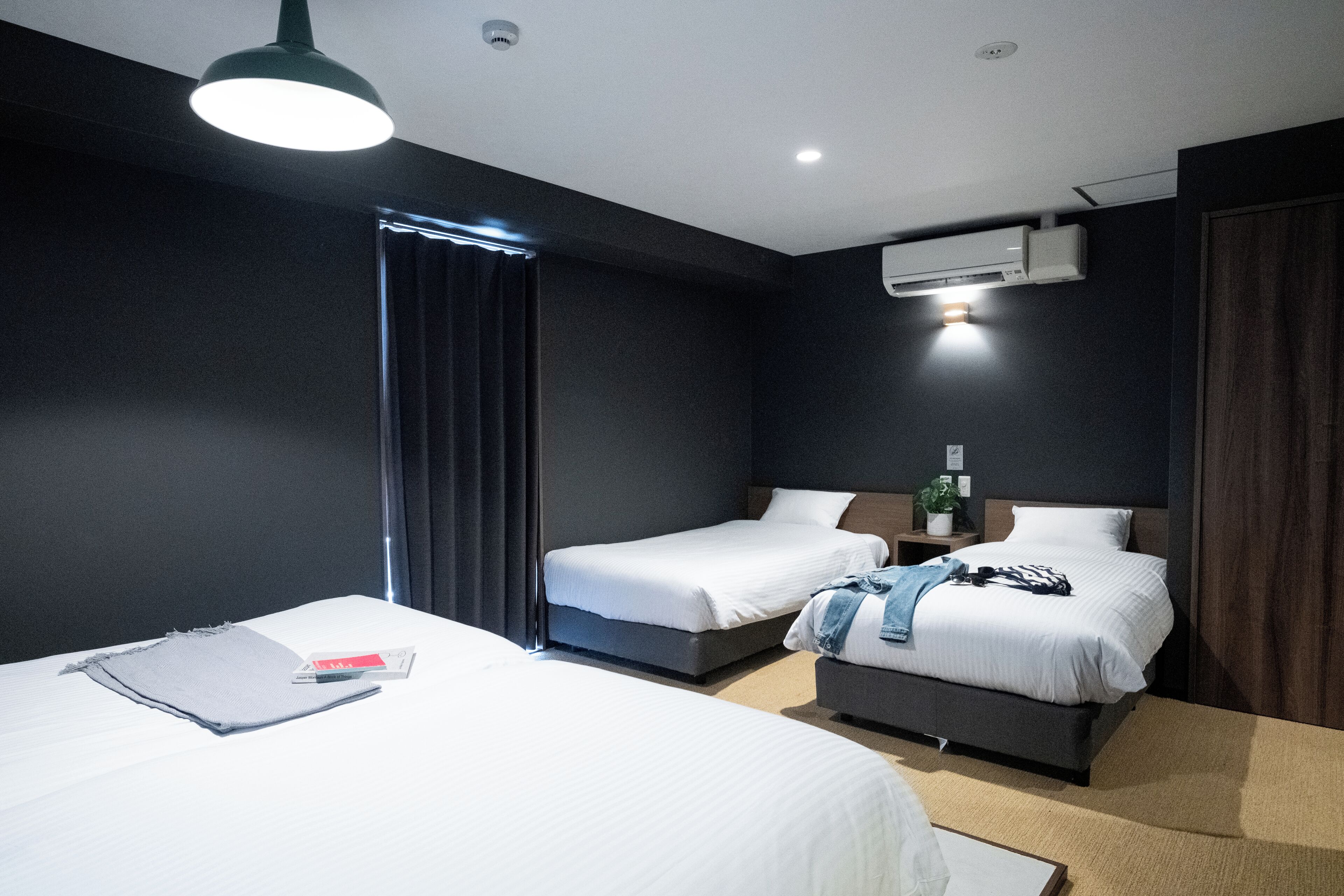 Ein Hotelzimmer mit zwei Betten, einem Schreibtisch und einem Fenster mit Vorhängen.