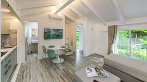 A modern interior with a dining area, a sofa, and a view of greenery outside. - AGAVE B&B (Vico Equense)