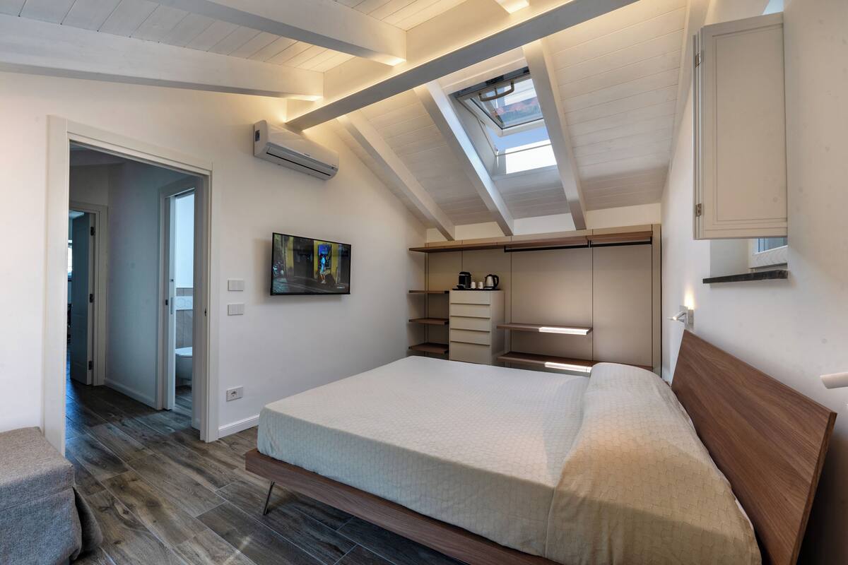 Un dormitorio con techo inclinado, tragaluces, armario empotrado y mesita de noche.