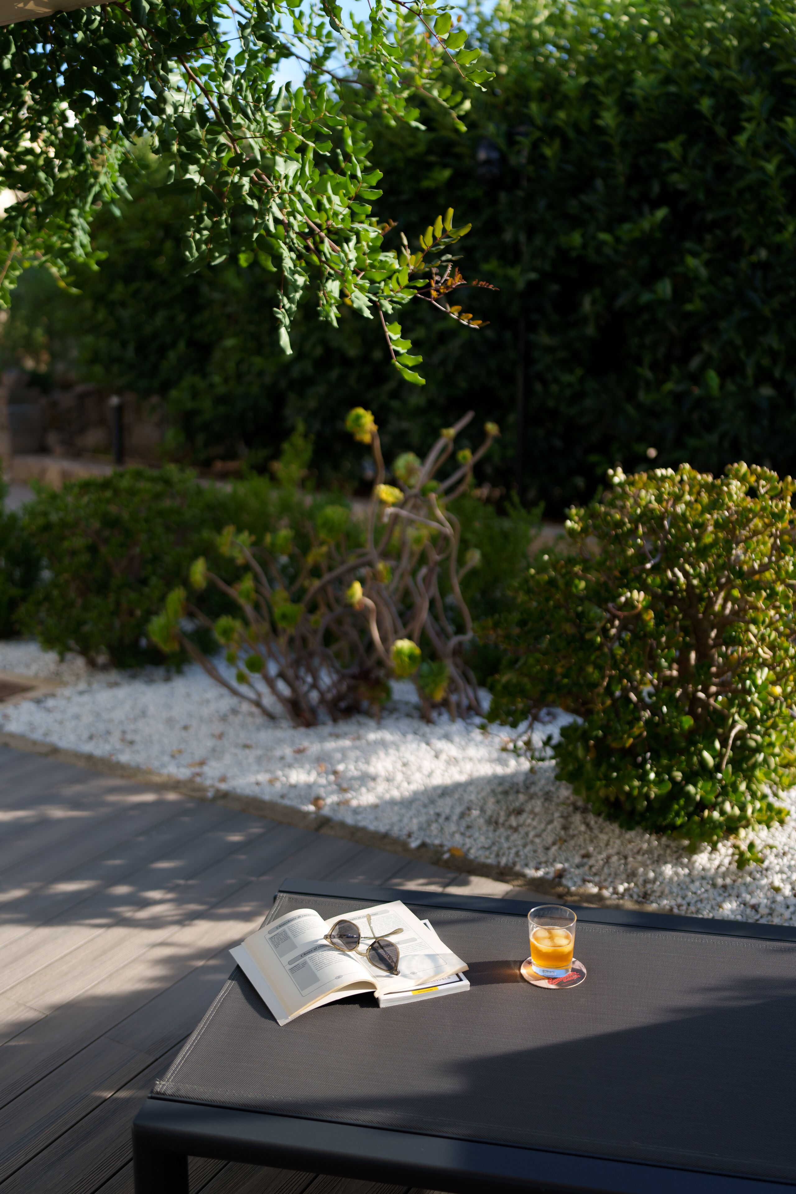 A table with a book, a pair of glasses, and a glass of drink.