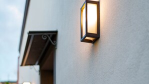 A building exterior with a white wall and a single wall-mounted light fixture. - AGAVE B&B (Vico Equense)