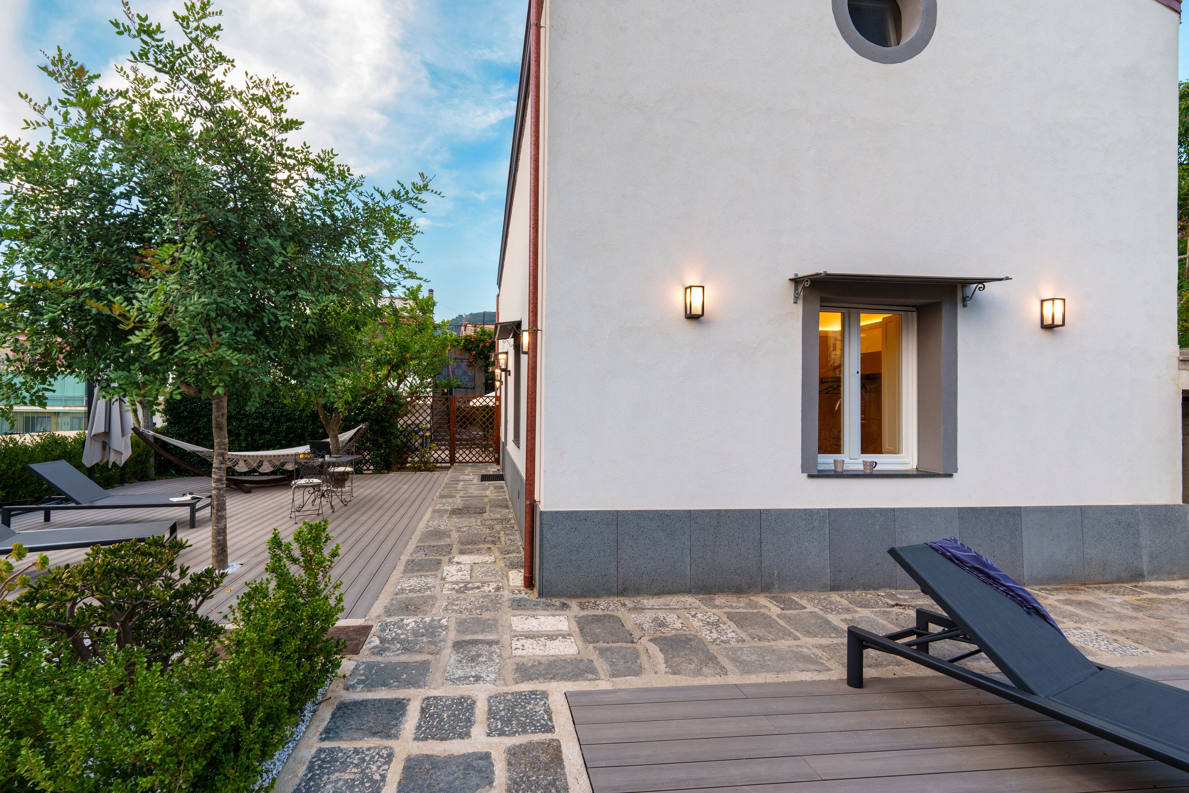 Un bâtiment moderne à l’extérieur blanc, doté d’une terrasse en bois et d’un fauteuil de relaxation.