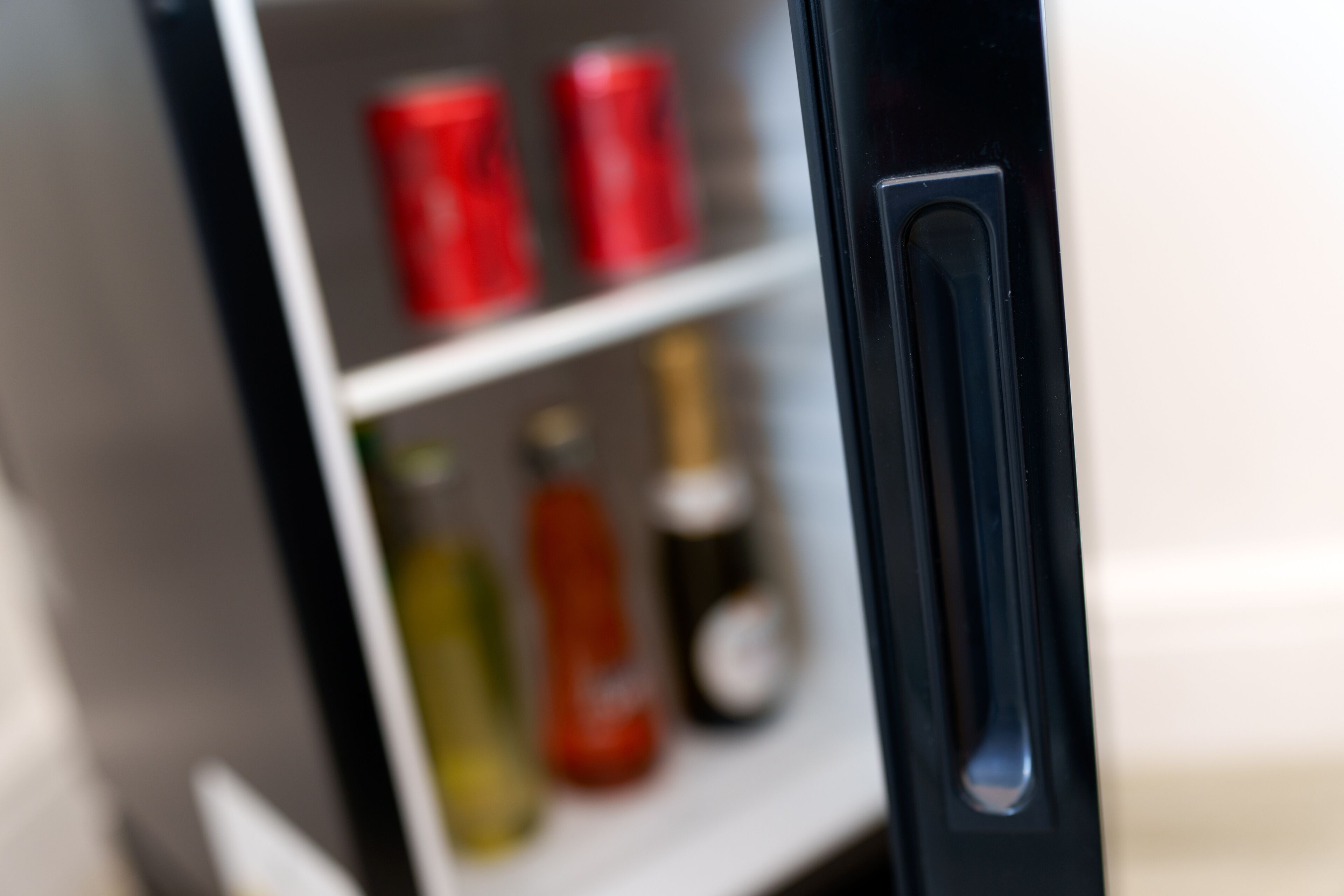 A close-up of a refrigerator with a shelf containing various bottles and cans.