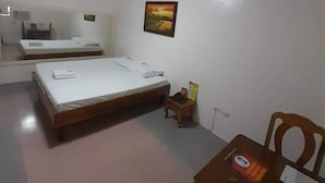 A room with two beds, a small table, a chair, and a wall-mounted picture. - OYO 1026 Evita Hotel Bacoor (Bacoor City)