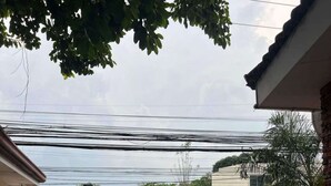 A residential street with a paved driveway leading to a house. There are multiple vehicles, including cars and motorcycles, on the road. Power lines are visible overhead. - OYO 1026 Evita Hotel Bacoor (Bacoor City)