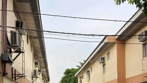 A narrow alleyway between two buildings with air conditioning units, fire extinguishers, and a green gate. - OYO 1026 Evita Hotel Bacoor (Bacoor City)