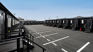 A parking lot with rows of portable cabins, each with a number on the door. - HOTEL R9 The Yard Shoo (Shoo)