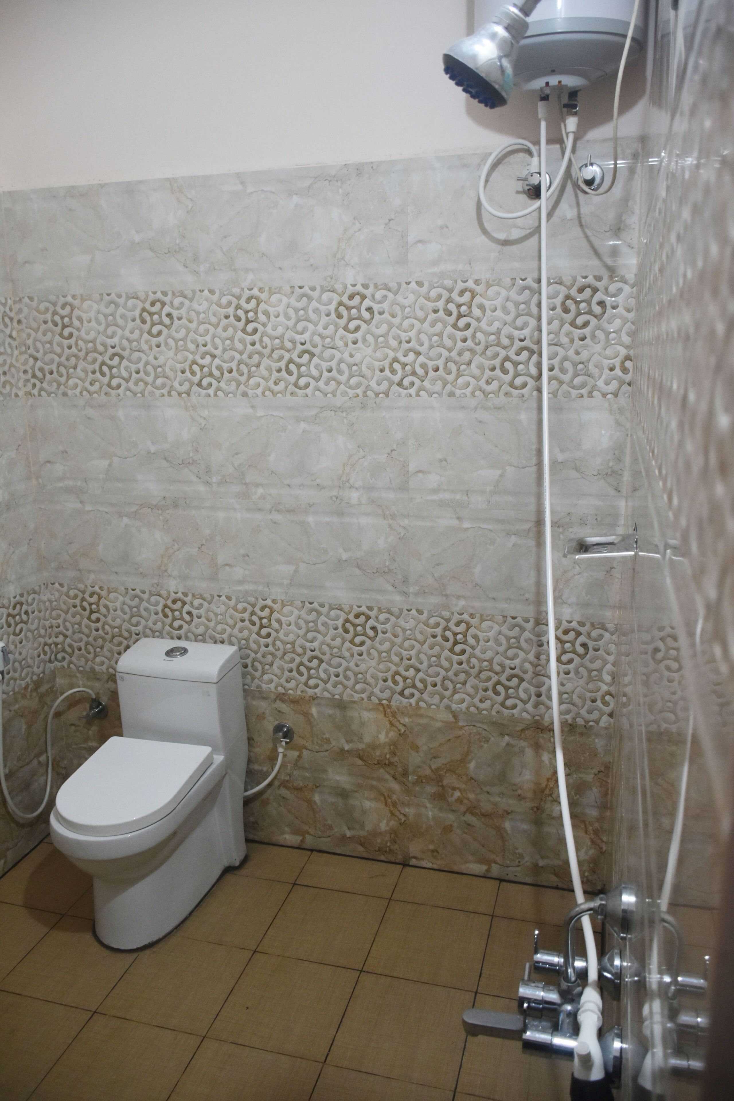 A bathroom with a toilet, shower, and decorative tiled walls.