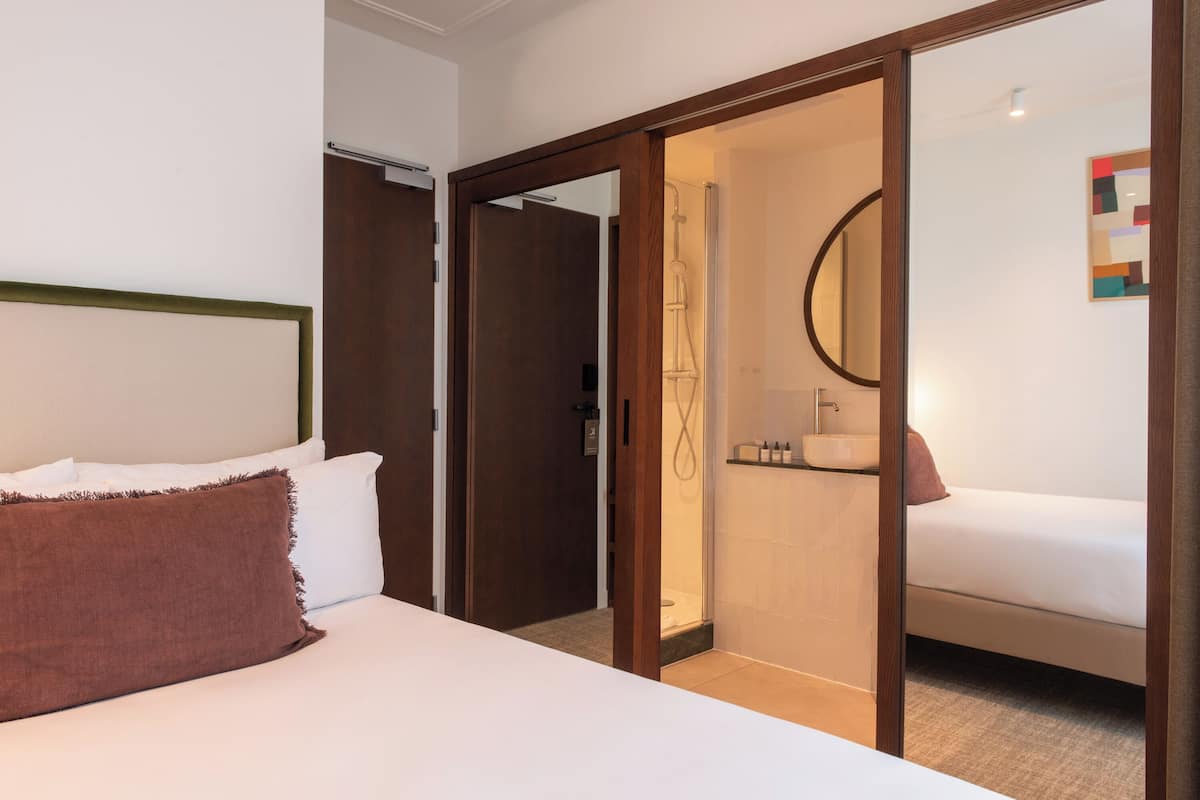 Une chambre d’hôtel avec un lit, une salle de bain avec douche et un miroir.