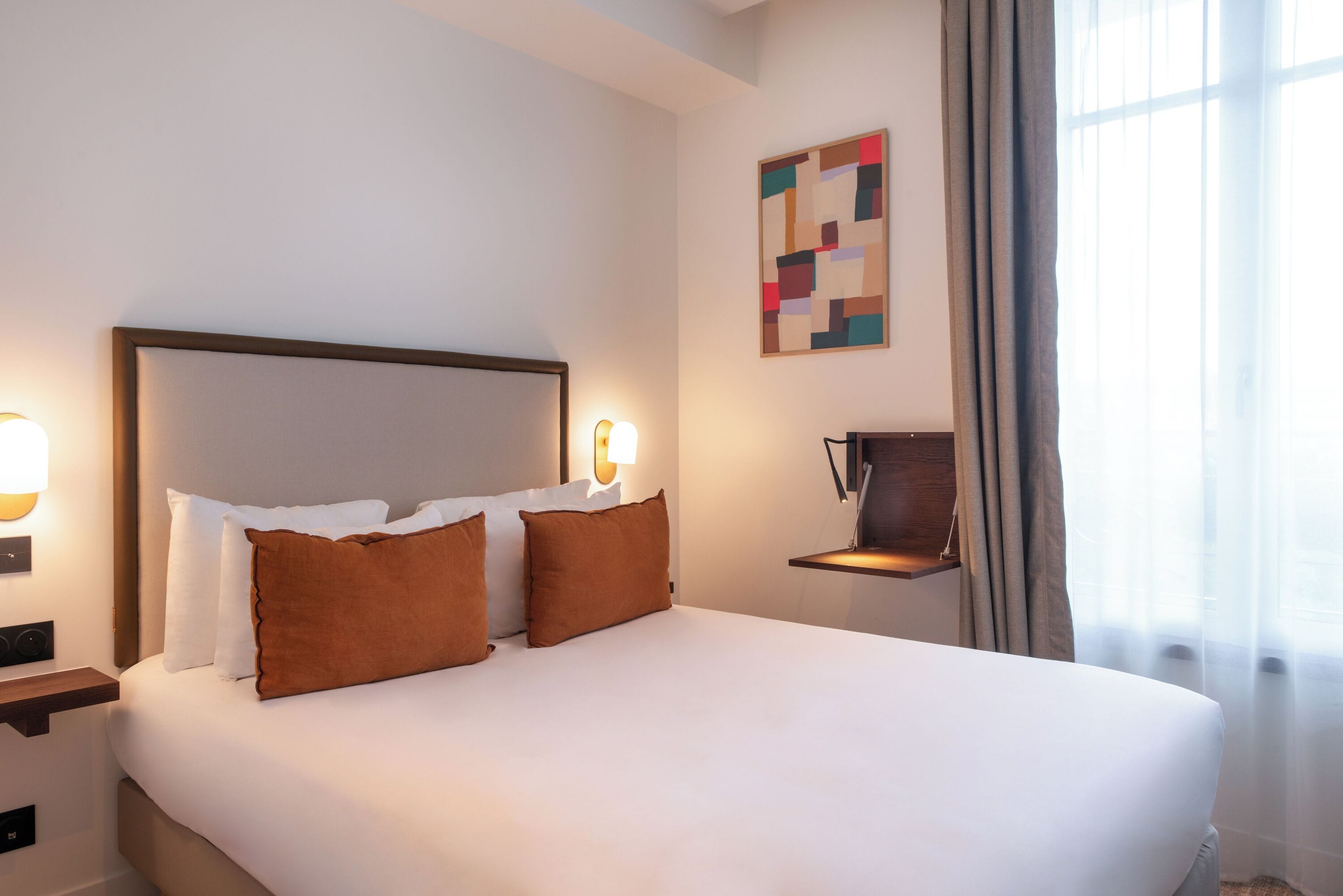 A neatly made bed with white and brown pillows, a headboard, and bedside lamps.