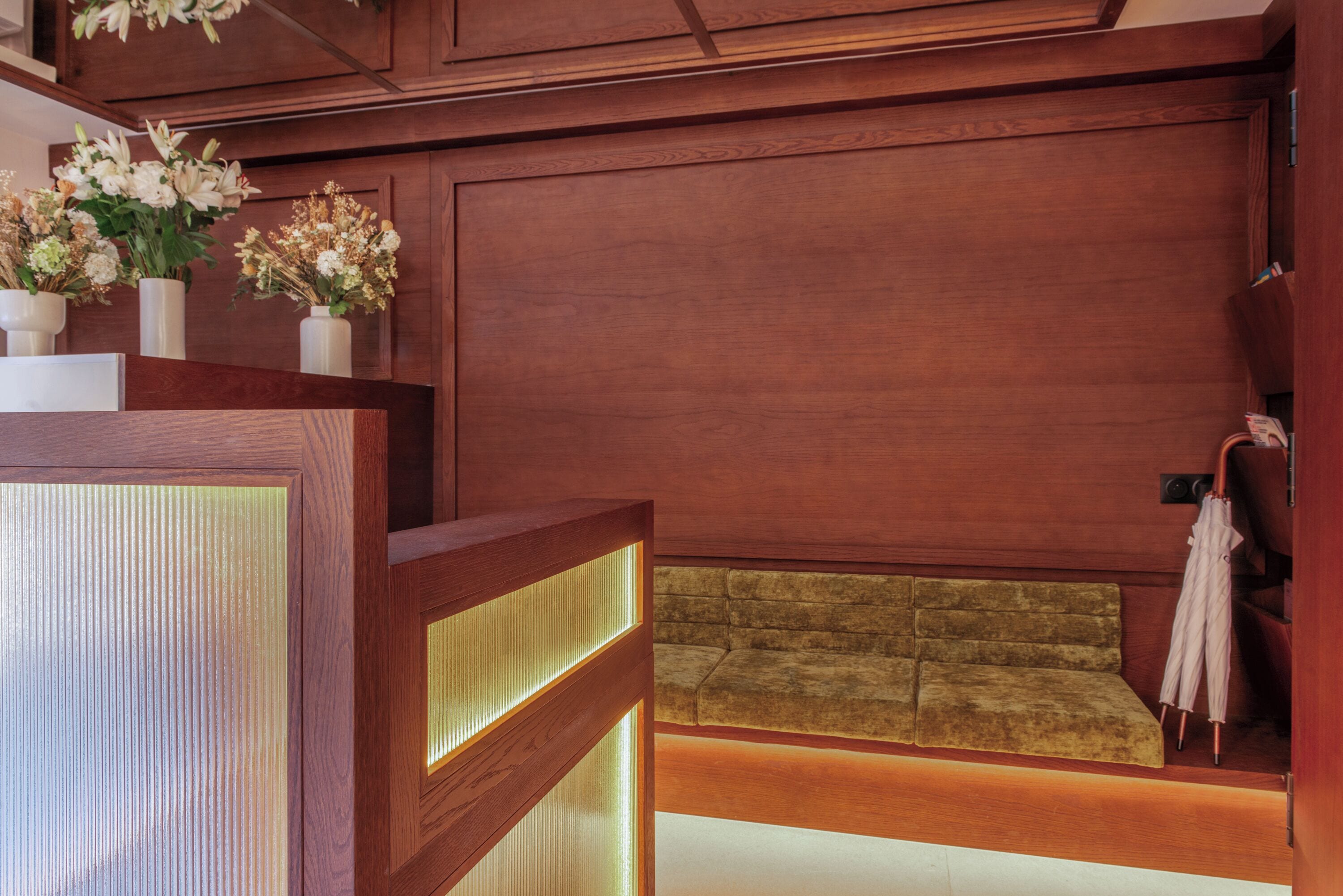 A reception area with a wooden reception desk, a cushioned bench, and a wall-mounted umbrella.