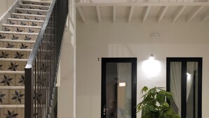 Un intérieur à plusieurs niveaux, avec un escalier, un extincteur et une plante en pot.