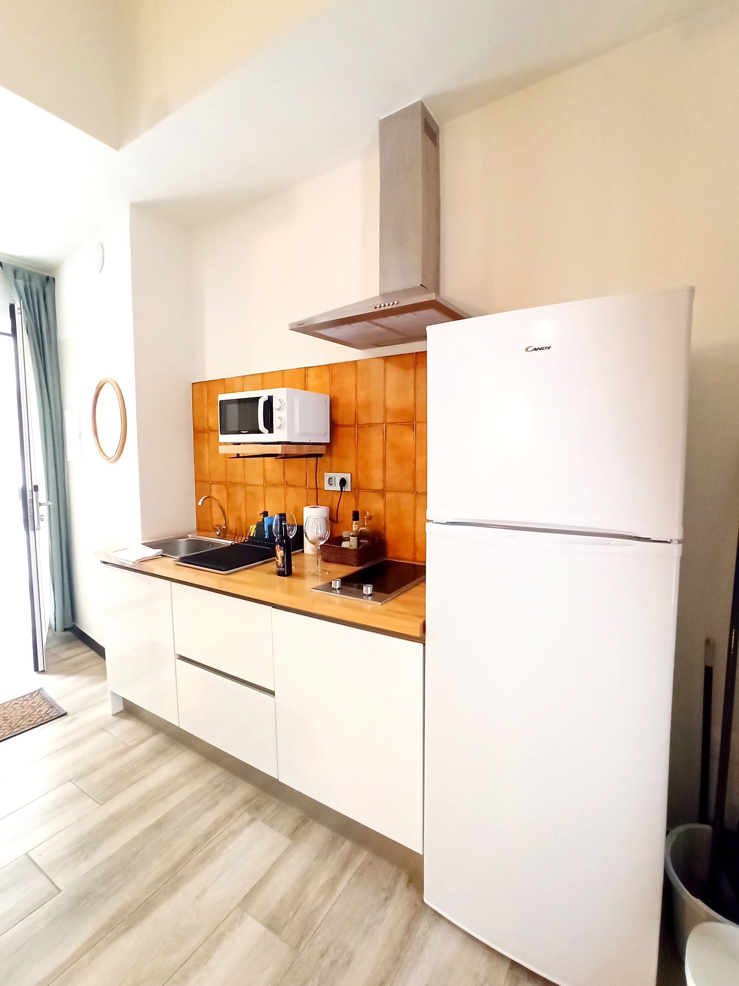 Una cocina moderna con microondas, estufa y refrigerador. Cuenta con un panel posterior de madera y una ventana con vistas.
