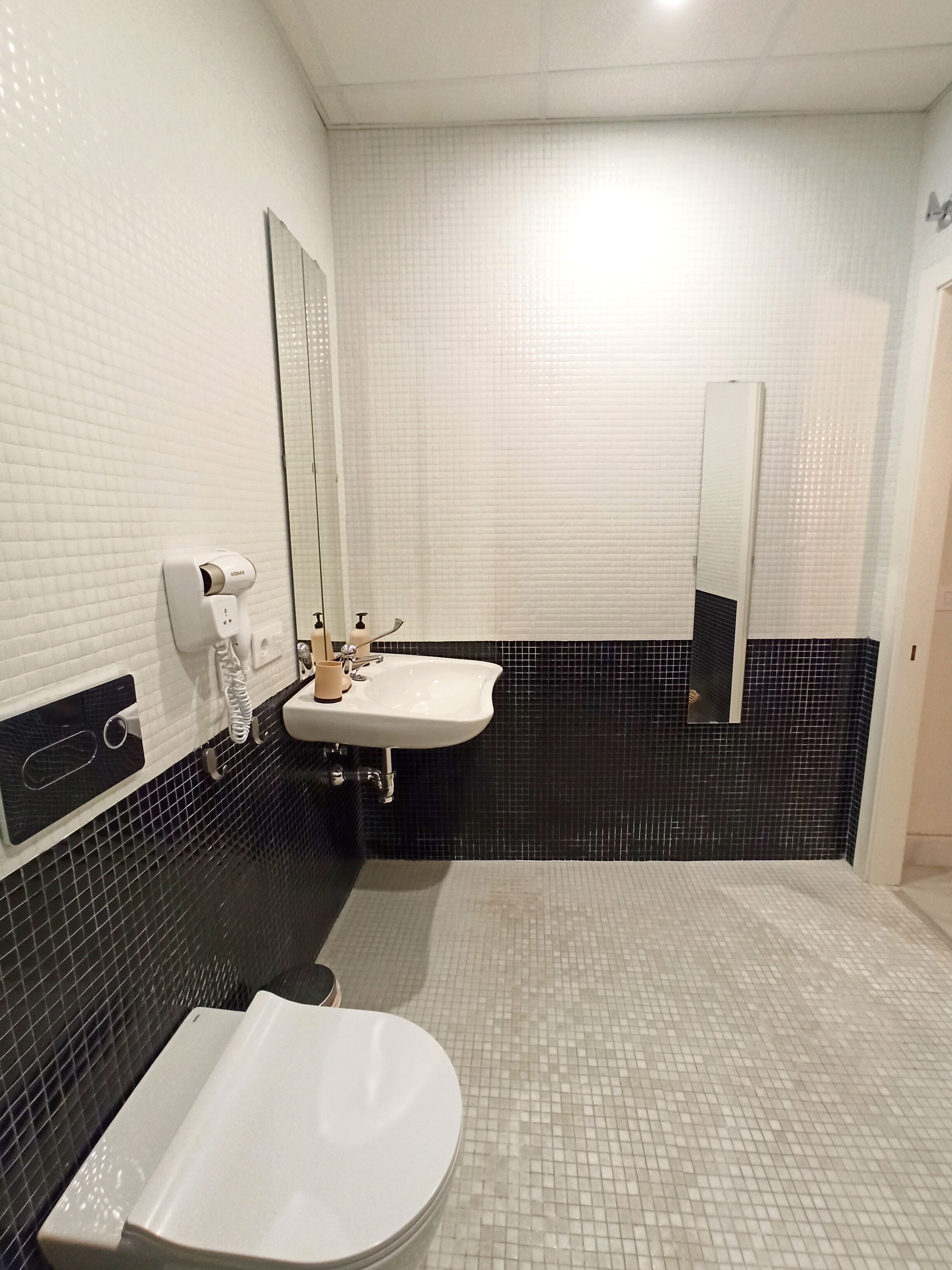 Un baño con un lavamanos blanco, un espejo y un inodoro.