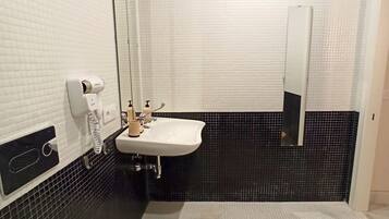 Un baño con un lavamanos blanco, un espejo y un inodoro.