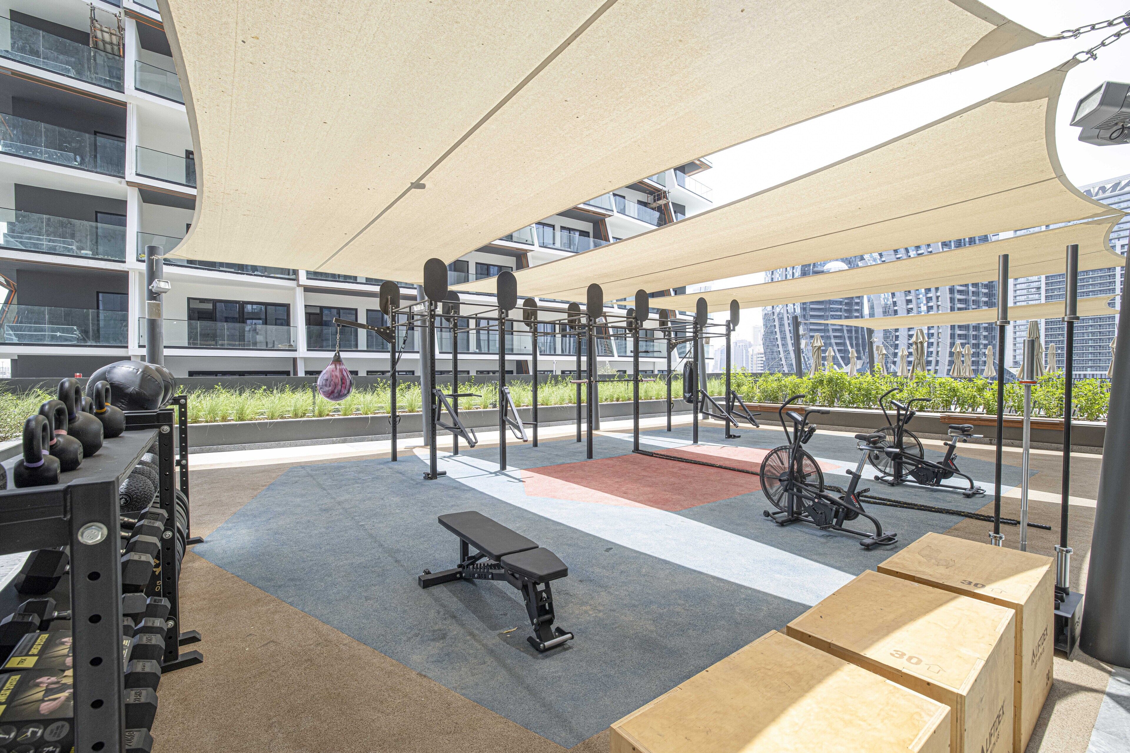 An outdoor gym with exercise equipment, a bench, and weight racks.