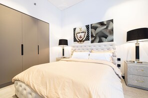 Une chambre à coucher avec un grand lit, deux tables de chevet, une armoire et deux œuvres d’art murales.