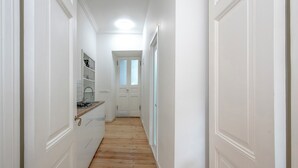 A narrow hallway with wooden flooring and white walls, leading to a door at the end. - HB apartments Tabukashvili (Tbilisi)