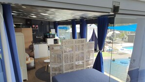 Une chambre comprenant un lit, une petite table, un élément de séparation décoratif et donnant sur une piscine extérieure.
