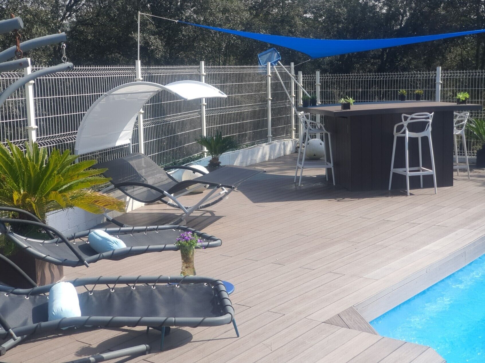 Area piscina con lettini, un bar e un patio recintato.