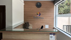 A reception desk with a wooden panel wall, a clock, and a logo for 'Palladium Luxury Suites'. - Palladium Luxury Suites Unit II (Hyderabad)