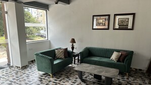 A living room with two green sofas, a coffee table, and a patterned floor. - Palladium Luxury Suites Unit II (Hyderabad)