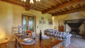 A dining area with a wooden table set for a meal, a sofa, and a fireplace. - Villa Chiara - Homelike Villas (Greve in Chianti)