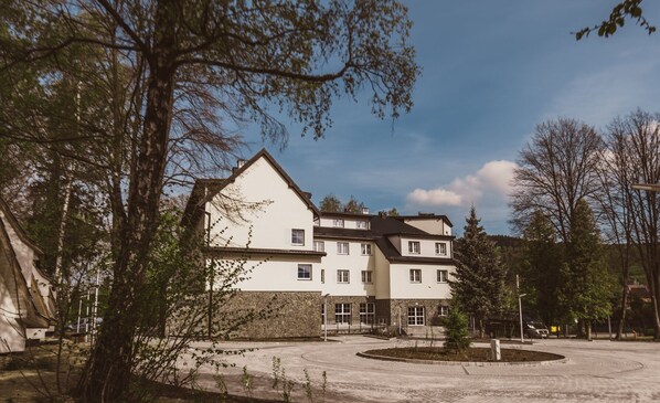 A multi-story building with a central courtyard, surrounded by trees and a clear sky. - Country Club Żywiec (Jelesnia)