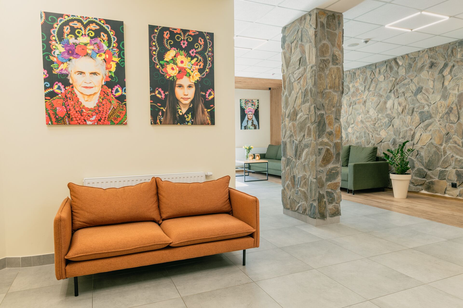 A lobby with a sofa, stone pillar, and artwork on the wall.