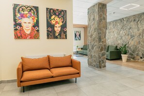 A lobby with a sofa, stone pillar, and artwork on the wall. - Country Club Żywiec (Jelesnia)
