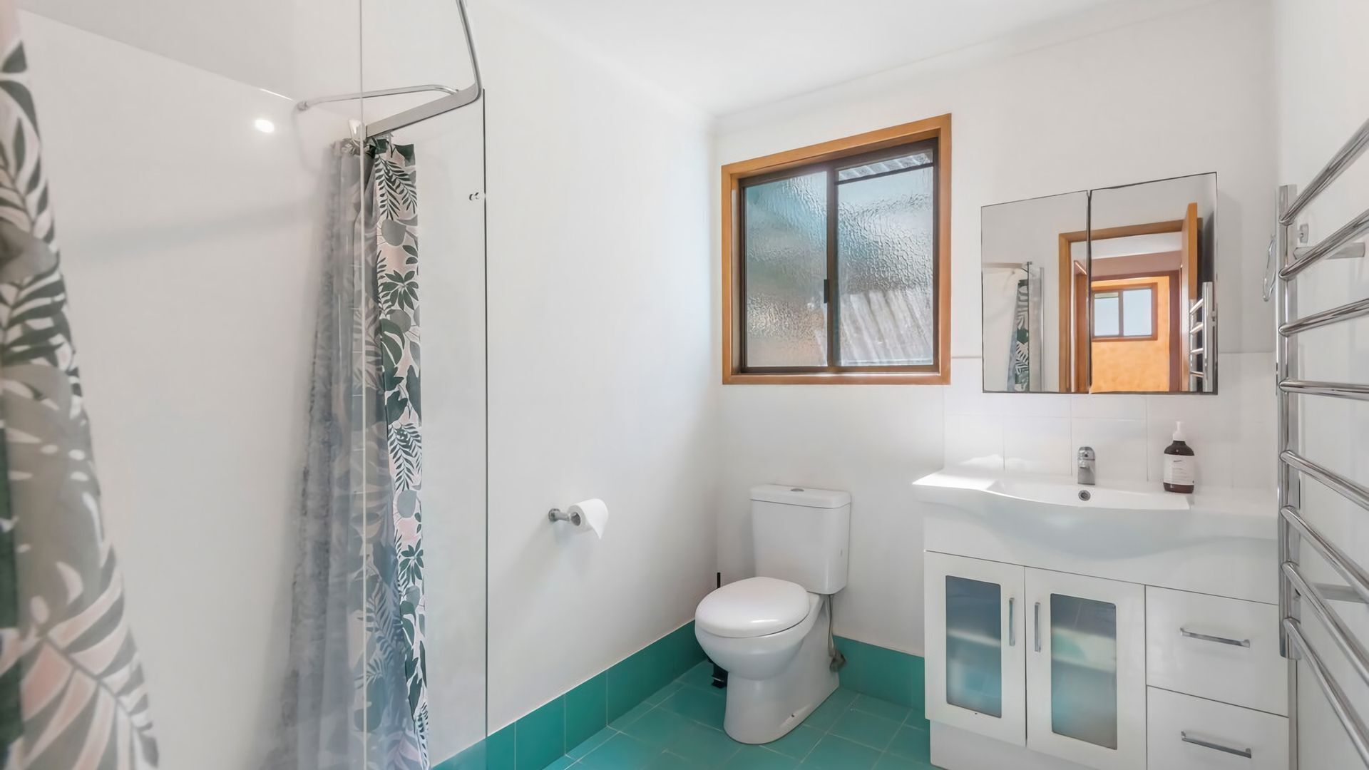 A bathroom with a toilet, a sink, and a shower area.
