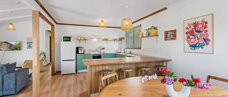 Une cuisine moderne avec des meubles en bois, un îlot central doté de tabourets et un éclairage suspendu.