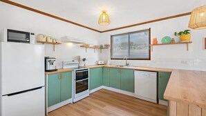 A compact kitchen with a microwave, coffee maker, toaster, oven, and dishwasher.